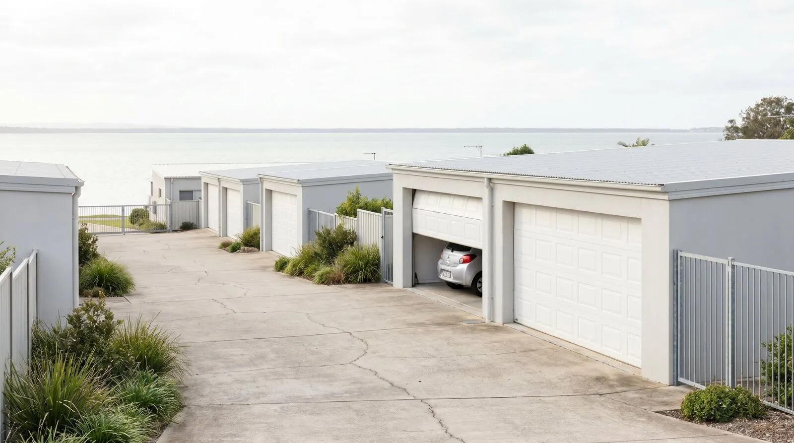 A row of white garage doors along a quiet villa complex driveway